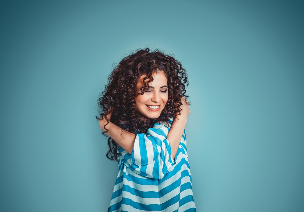 a woman smiling and hugging herself