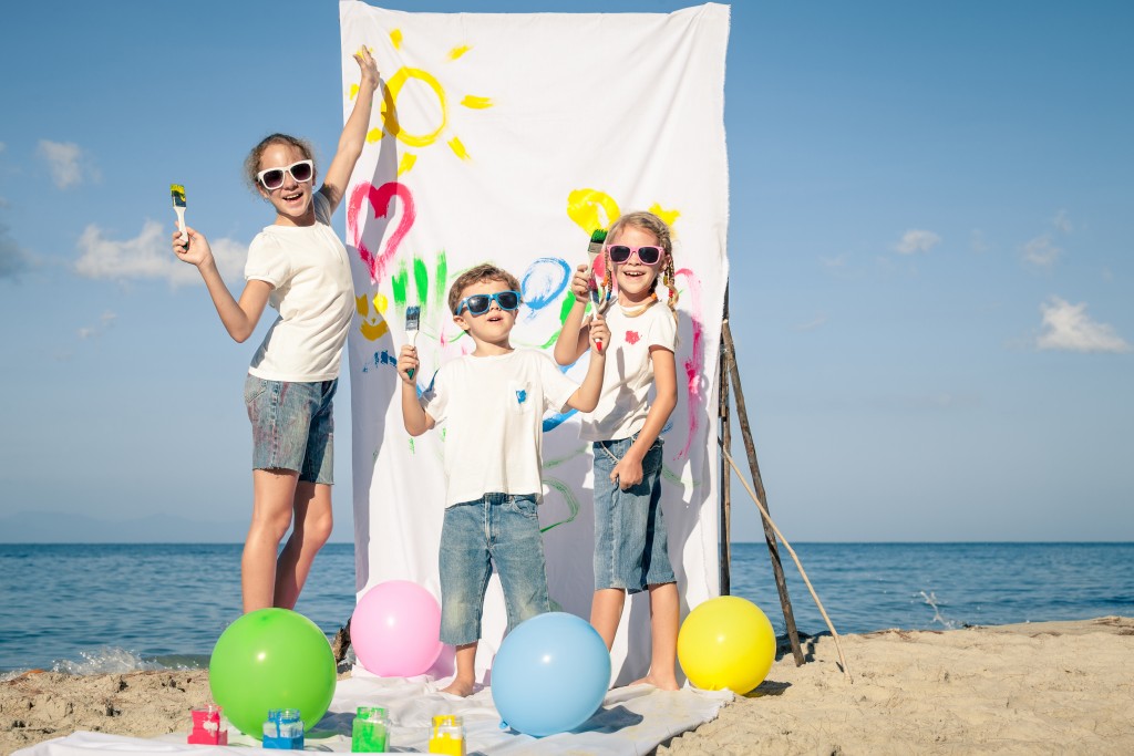 children playing with paint on the beach