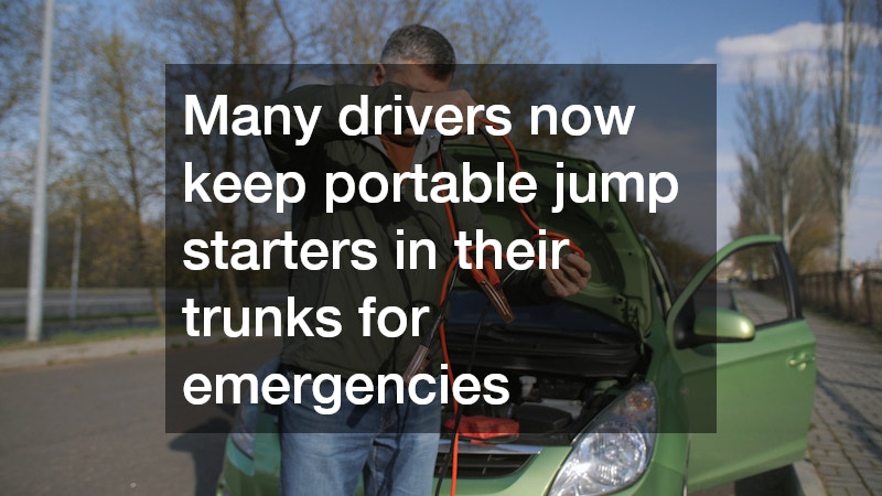 man holding jumper cables with a car's open hood in the background